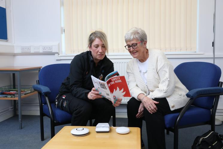 Volunteer showing a Home Fire Safety booklet to a member of the public