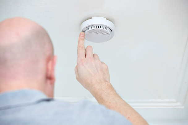 man testing smoke alarm