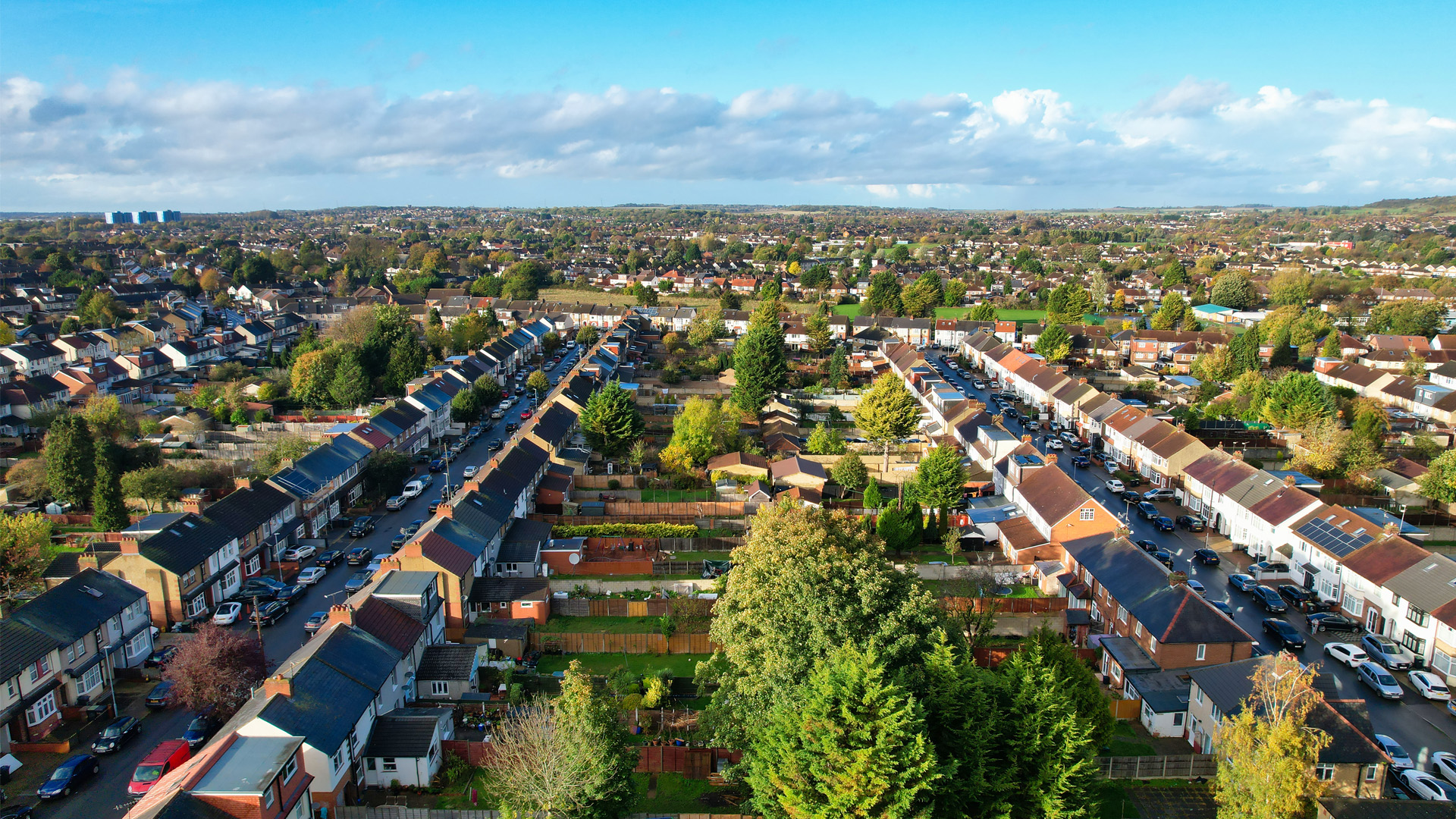 A picture of a street in Luton, terraced houses and their gardens are visable with a clear blue sky above.