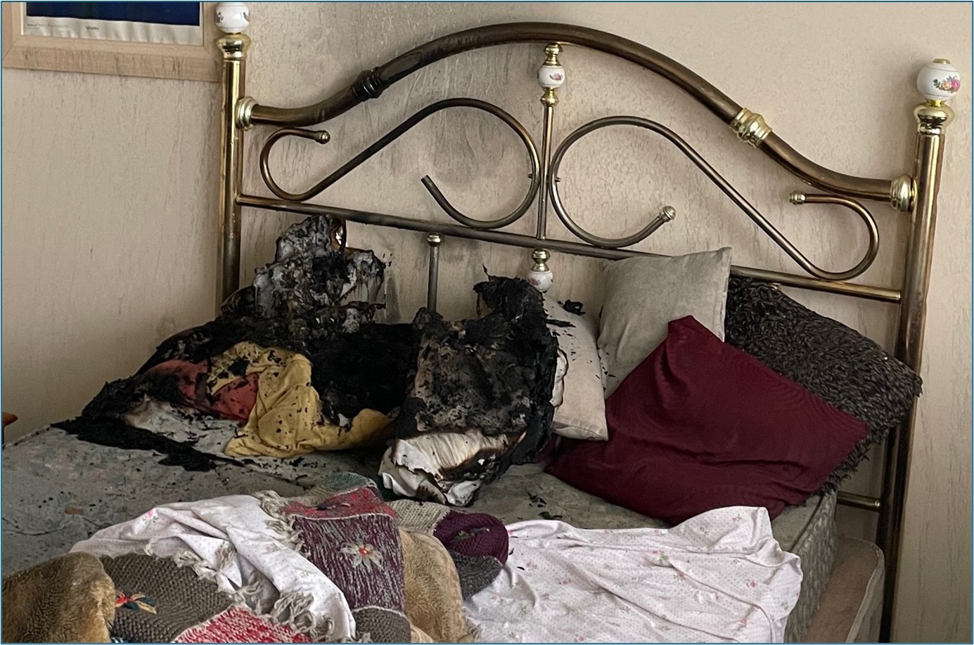 Photograph of bed that caught fire at Roise Court, Bedford. Shows bedding damaged by fire.