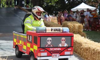 Man in a helmet and hi-vis jacket driving a soapbox kart