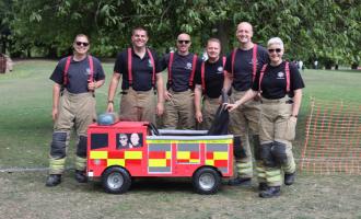 Six firefighters standing by a soapbox kart